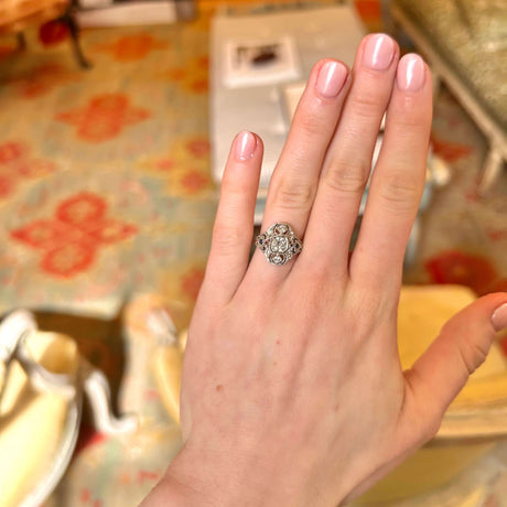 Hand wearing the art deco cluster diamond and sapphire ring held out against a colourful carpet