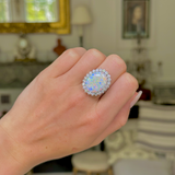 White opal and diamond cluster ring, worn on hand.