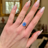 Solitaire sapphire engagement ring worn on hand. 