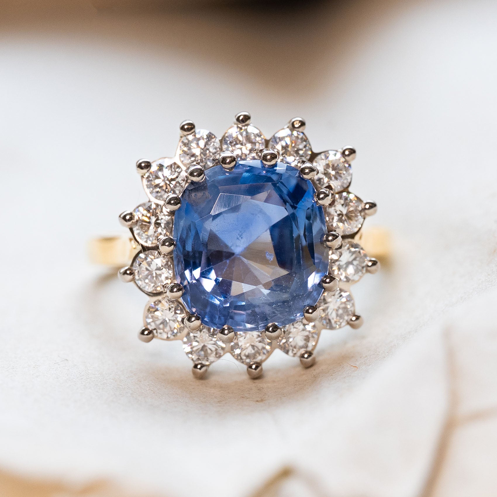 Antique inspired, Ceylon blue sapphire with a diamond halo set in white gold with a yellow gold band. 