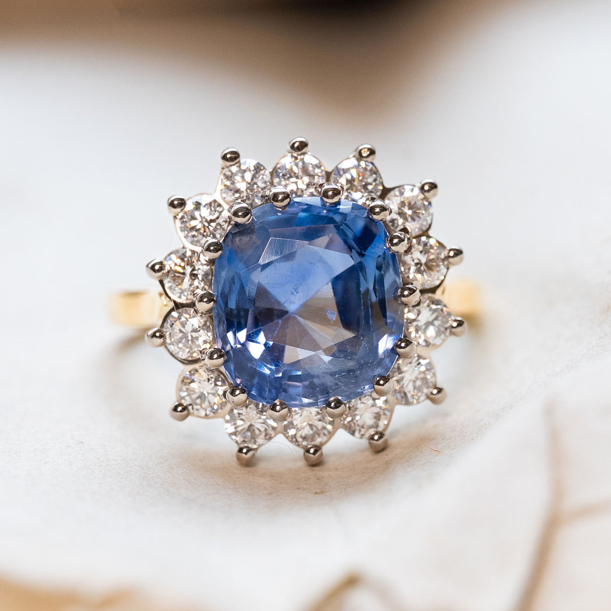 Antique inspired, Ceylon blue sapphire with a diamond halo set in white gold with a yellow gold band. 