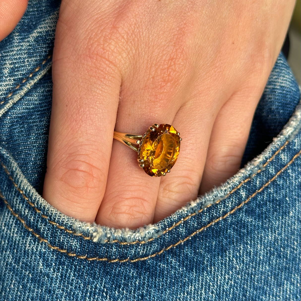 citrine cocktail ring worn on hand in pocket of jeans.