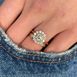 Diamond cluster yellow gold engagement ring paired with wedding band showing scale. 