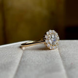 Diamond cluster yellow gold engagement ring angled to show details of setting. 