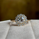 Diamond cluster yellow gold engagement ring on captured front on to show principal diamond. 