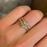 Diamond three-stone engagement ring worn on hand close up with wedding band 
