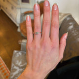 Diamond three-stone engagement ring worn on the hand to show scale 