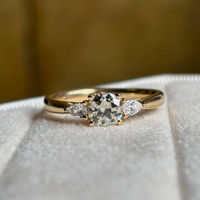 Diamond three-stone engagement ring on a blurred background to show diamond clarity and colour. 