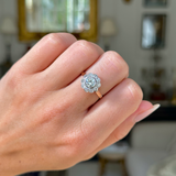 antique diamond cluster engagement ring, worn on closed hand, front view.