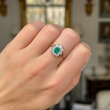 Edwardian emerald and diamond cluster ring worn on closed hand.