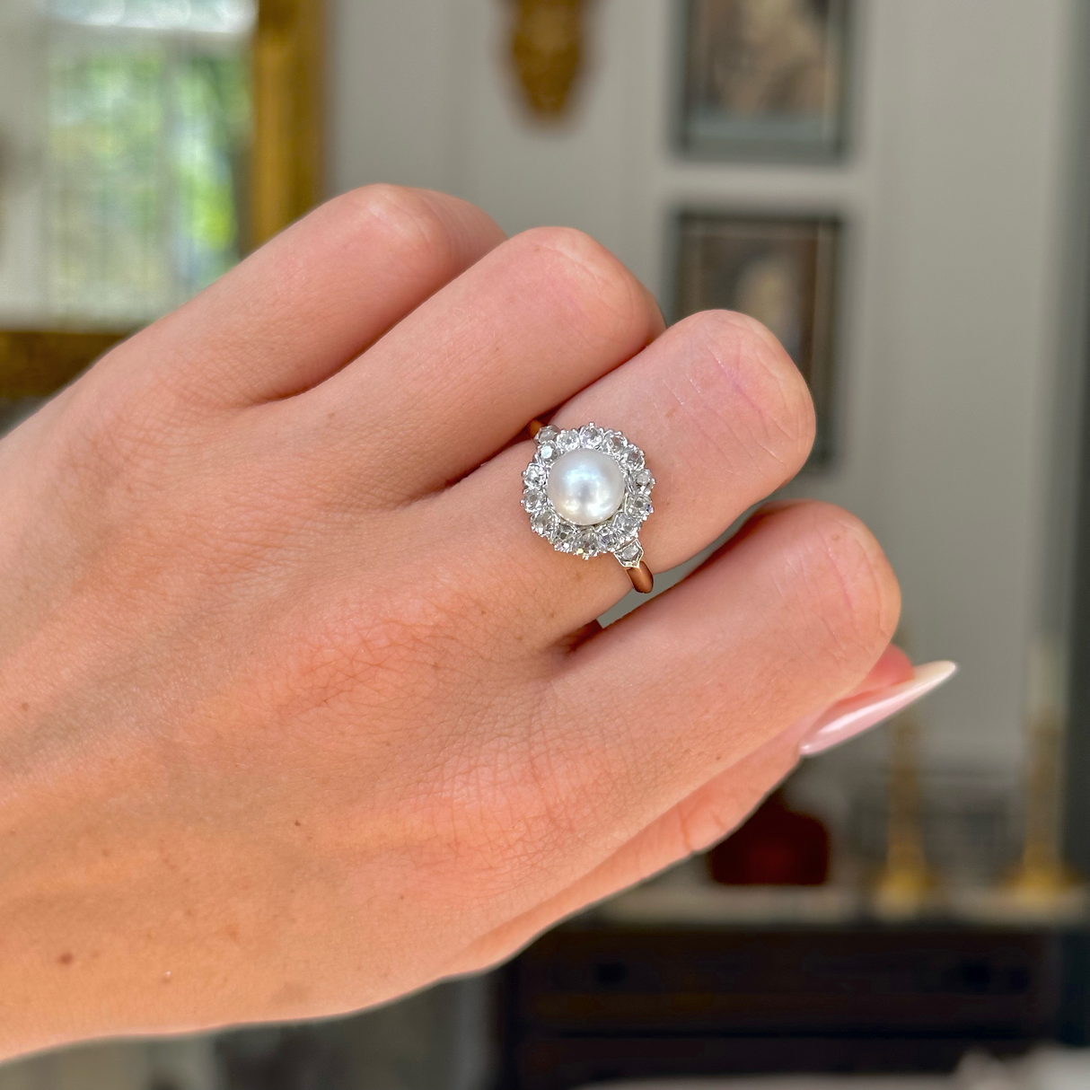 Antique pearl and diamond cluster ring worn on closed hand. 