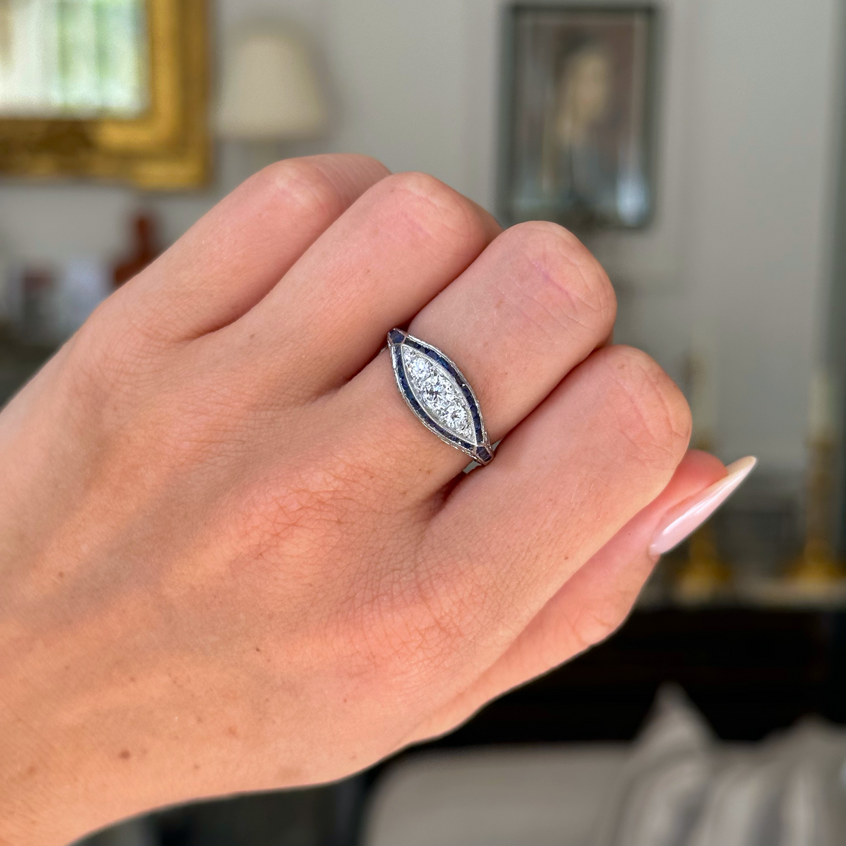 Antique Edwardian sapphire and diamond ring worn on closed hand. 