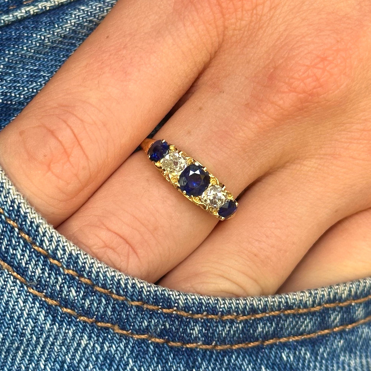 edwardian sapphire and diamond five stone ring worn on hand in pocket of jeans. 