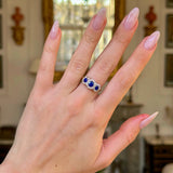 sapphire and diamond triple cluster ring worn on hand. 