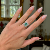 square-cut emerald and diamond cluster ring, worn on hand, front view.