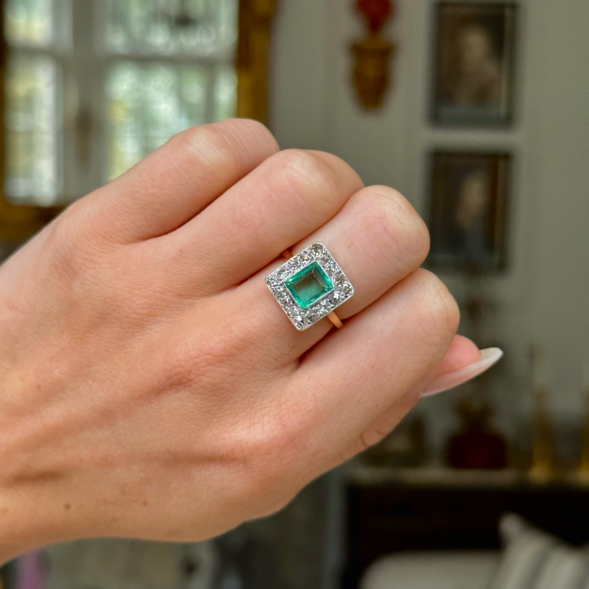 square-cut emerald and diamond cluster ring, worn closed hand, front view.