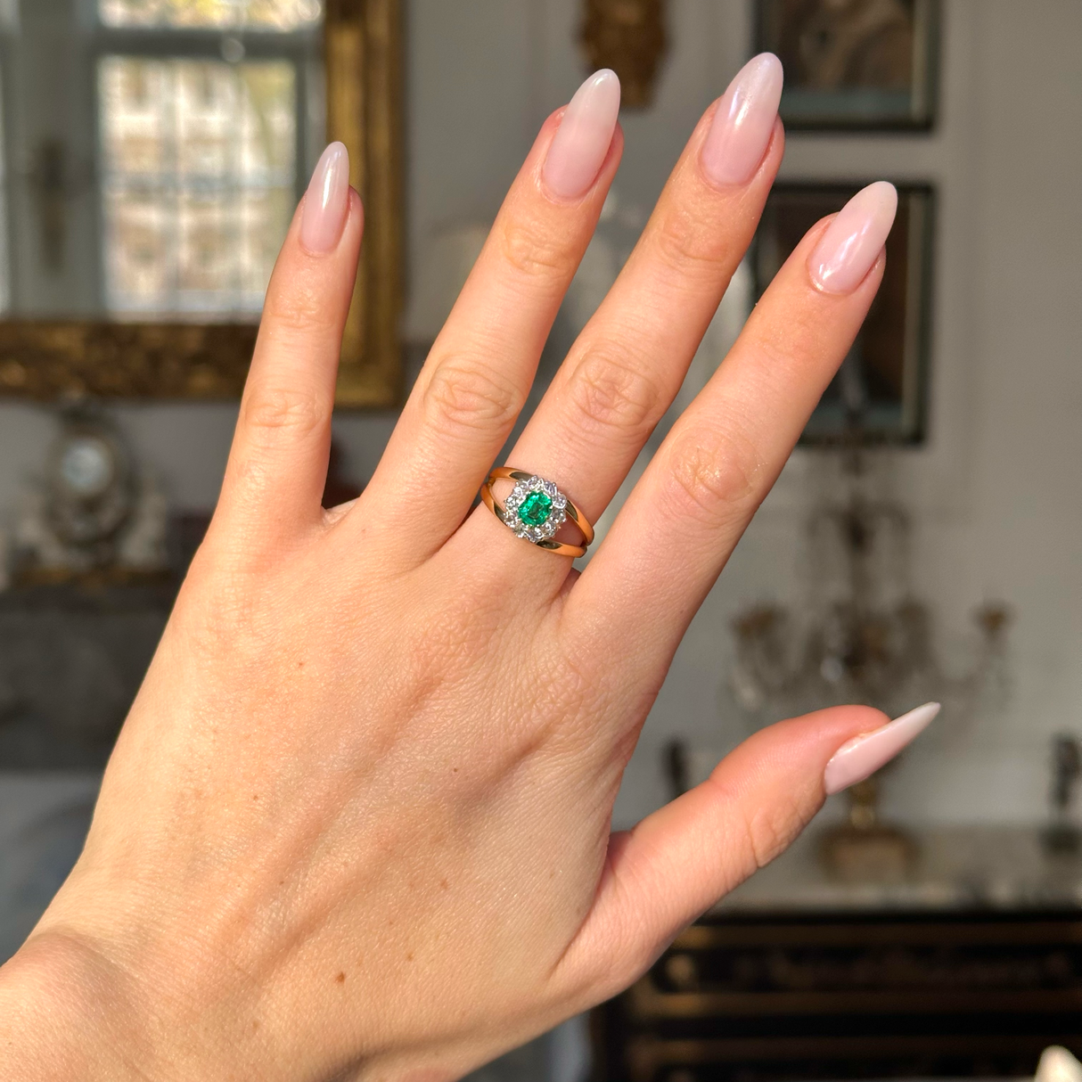 Vintage emerald and diamond cluster ring on hand. 