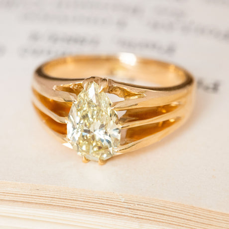 An antique yellow pear-cut diamond solitaire gold ring with open work shoulders.