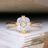 An antique-inspired, warm toned cushion-cut diamond solitaire ring in yellow gold.