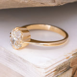 A vintage-inspired, cushion-cut diamond solitaire ring in 18ct yellow gold showing the side profile.