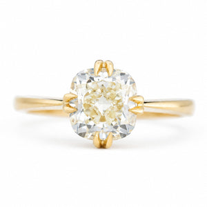 An antique-inspired, yellow-toned cushion-cut diamond solitaire ring in yellow gold.