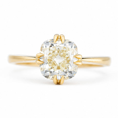 An antique-inspired, yellow-toned cushion-cut diamond solitaire ring in yellow gold.