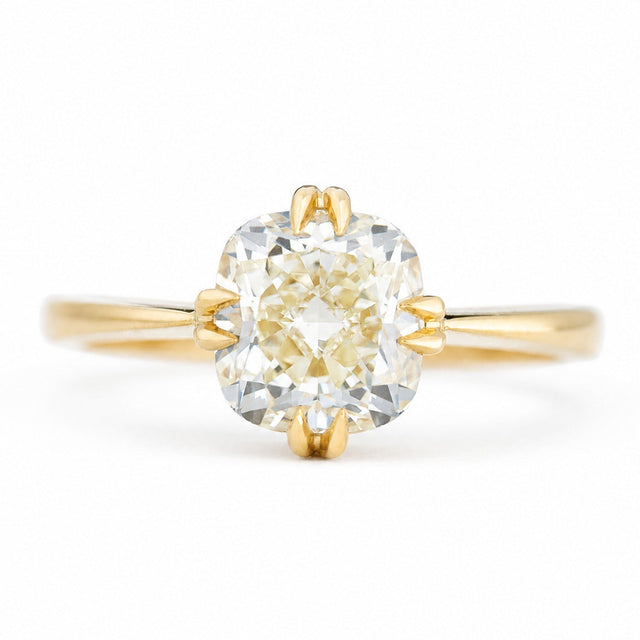 An antique-inspired, yellow-toned cushion-cut diamond solitaire ring in yellow gold.