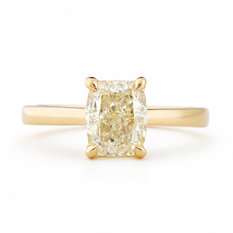 Antique-inspired, cushion-cut diamond solitaire engagement ring in yellow gold against a white background
