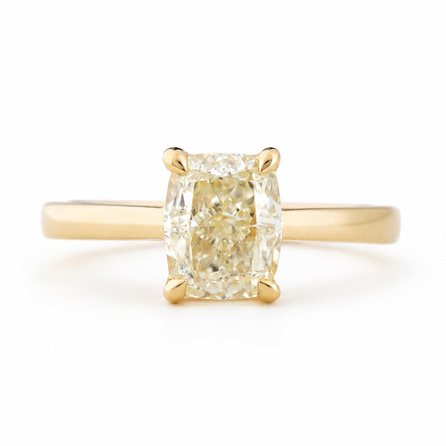 Antique-inspired, cushion-cut diamond solitaire engagement ring in yellow gold against a white background