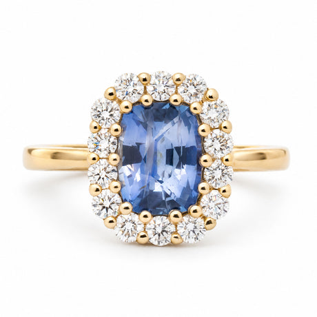 Front view of an antique-inspired cushion-cut blue sapphire engagement ring in 14ct yellow gold, surrounded by a halo of round brilliant-cut diamonds.