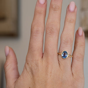 Blue sapphire solitaire engagement ring worn on the hand, showing the elegant proportions of its minimal antique-inspired design.