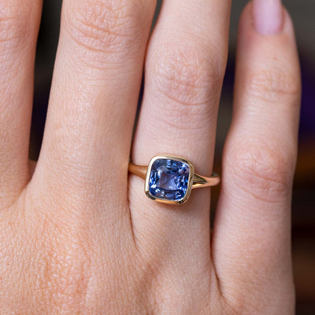 A close-up image of a hand wearing an Antique-inspired blue sapphire solitaire ring in yellow gold.