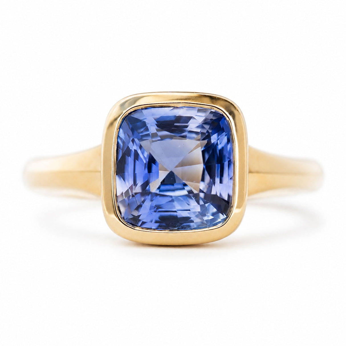 An antique-inspired blue sapphire solitaire ring in yellow gold against a white background.