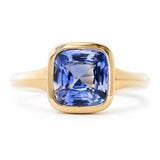 An antique-inspired blue sapphire solitaire ring in yellow gold against a white background.