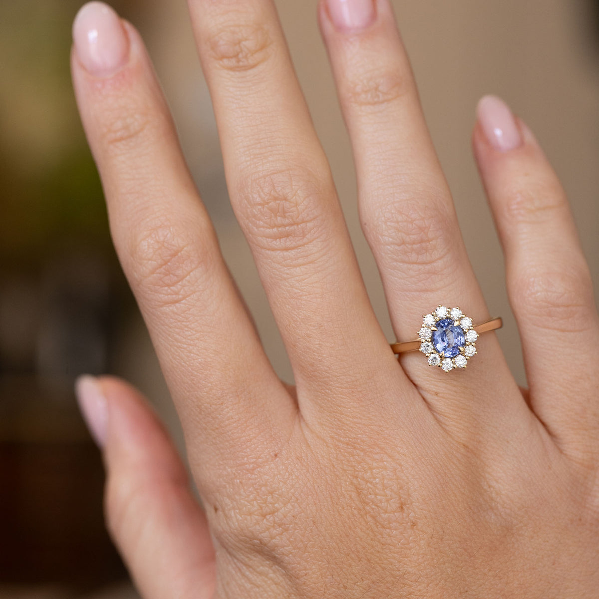 Antique-inspired blue sapphire engagement ring worn on the hand, displaying the elegant scale of its oval diamond cluster.