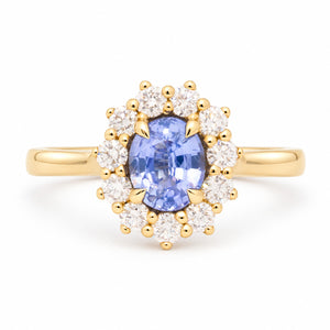 Antique-inspired oval-cut blue sapphire and diamond cluster engagement ring in yellow gold, framed by a halo of round diamonds.