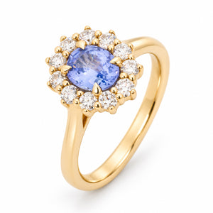 Three-quarter studio portrait of the sapphire cluster ring, showcasing its pale blue oval centre, diamond surround and polished gold band.