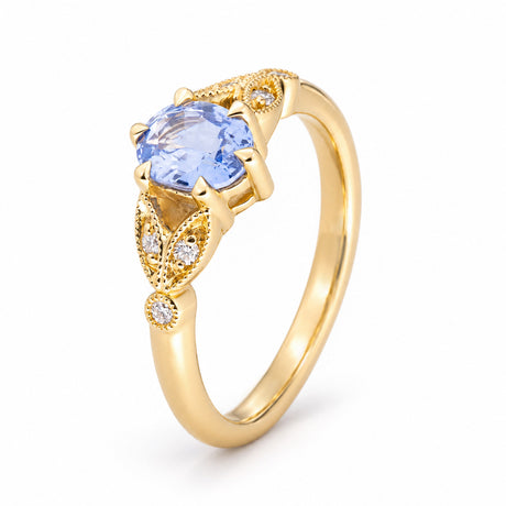 Sculptural studio view of the sapphire ring, revealing its oval centre stone, detailed gold shoulders and delicate diamond settings.
