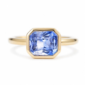 A close-up of an antique-inspired, violet-blue sapphire solitaire engagement ring set in 14ct yellow gold.