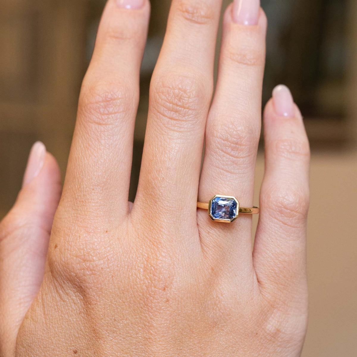 Blue sapphire solitaire ring in yellow gold showcased on the hand with an antique-inspired design.