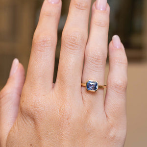 Blue sapphire solitaire ring in yellow gold showcased on the hand with an antique-inspired design.