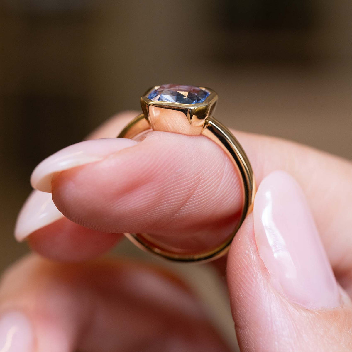Side profile of an antique-inspired bezel-set blue sapphire solitaire engagement ring in yellow gold.