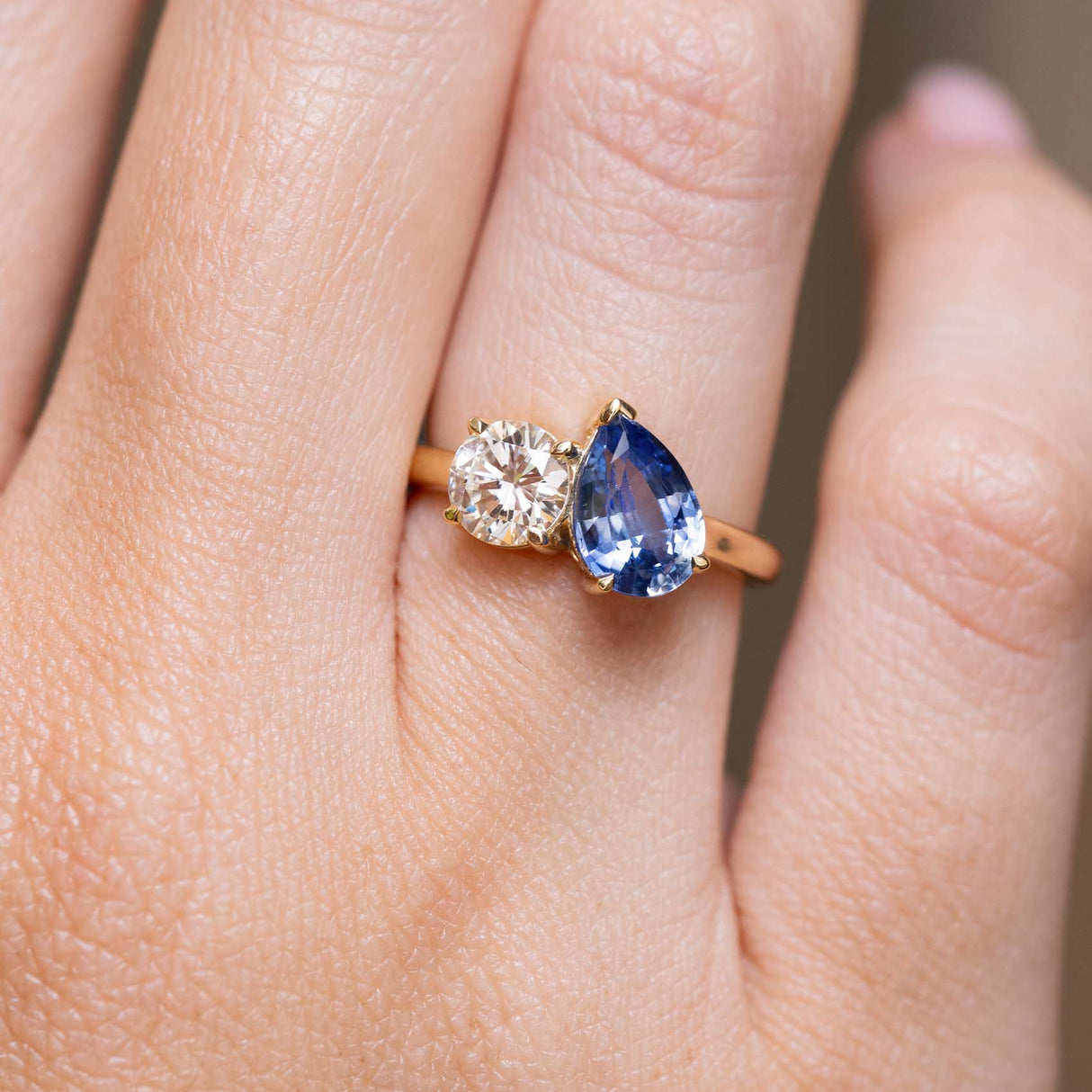 Sapphire and diamond Toi et Moi engagement ring worn on the finger