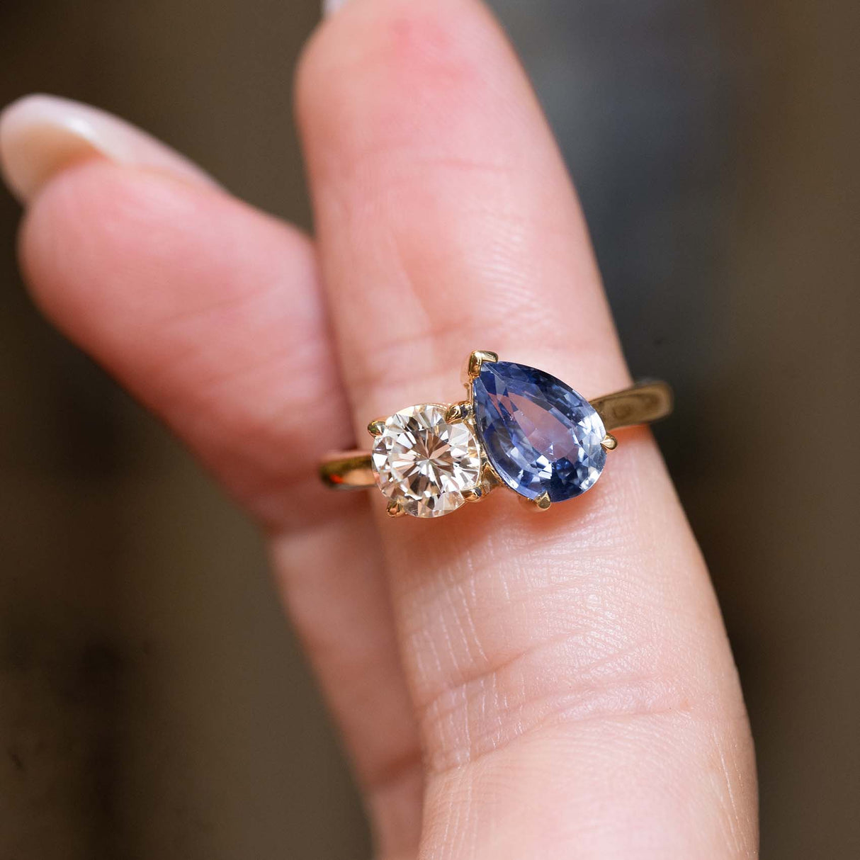 Sapphire and diamond Toi et Moi ring balanced on the finger