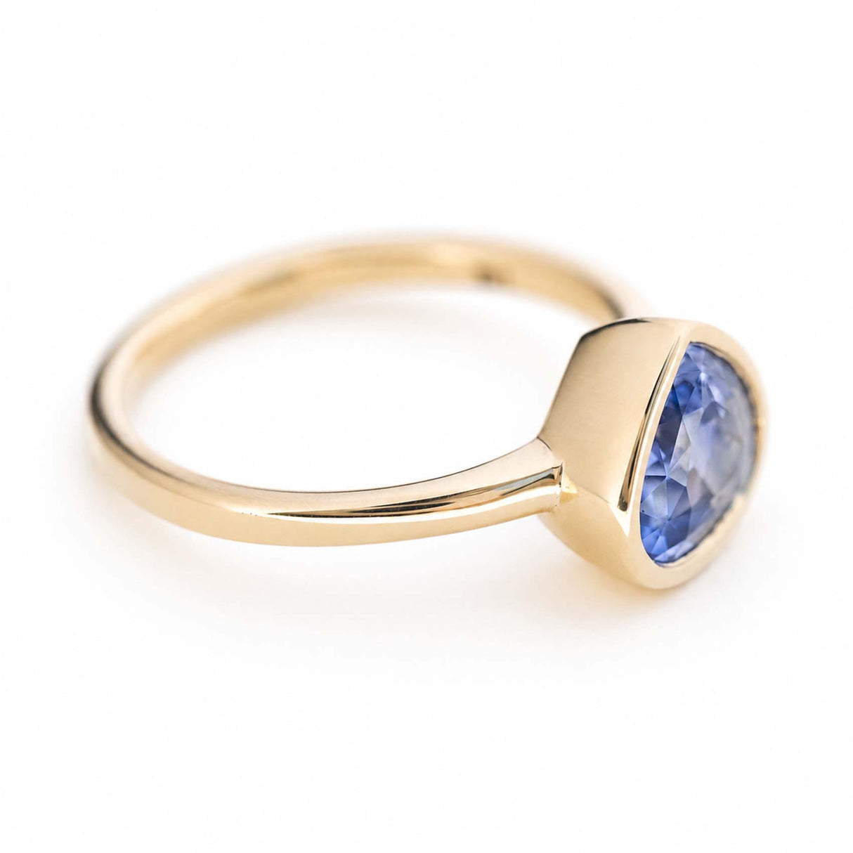 An antique-inspired, violet-blue sapphire solitaire engagement ring set in yellow gold.