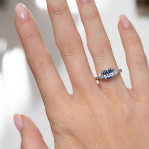 Blue sapphire three-stone engagement ring worn on a hand, showcasing its striking blue gemstone and elegant proportions.