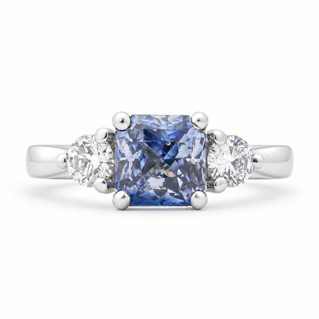 Antique-inspired blue sapphire and diamond three-stone engagement ring in platinum, featuring a square cushion-cut sapphire and two round brilliant-cut diamonds.