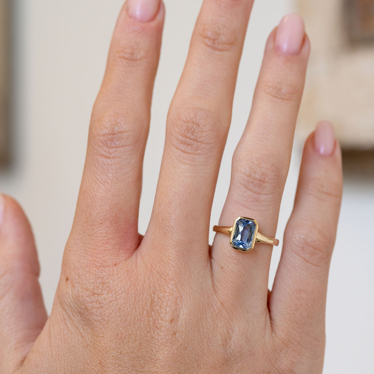Antique-inspired sapphire solitaire worn on the hand, showing the elegant proportions of its rectangular blue gemstone.