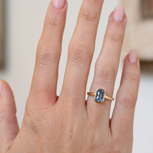 Antique-inspired sapphire solitaire worn on the hand, showing the elegant proportions of its rectangular blue gemstone.