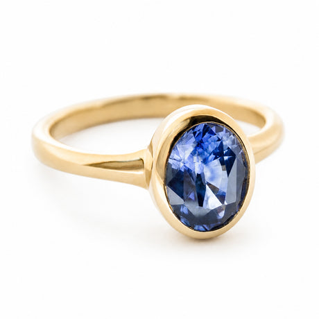 A side view of a vintage-inspired 14ct yellow gold ring set with an oval deep blue sapphire. 
